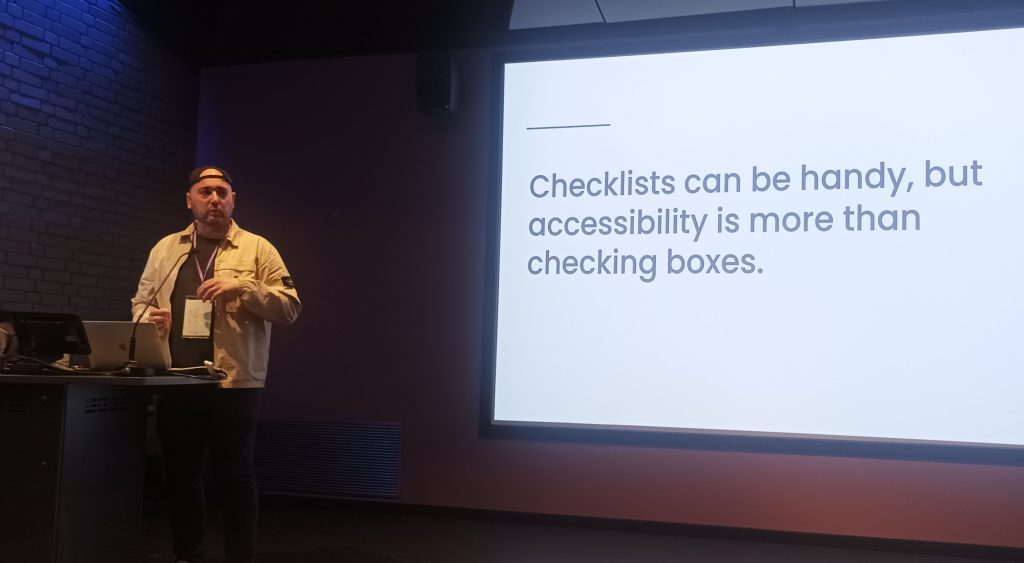 Shaun Conner presenting next to a slide reading 'Checklists can be handy, but accessibility is more than checking boxes'.